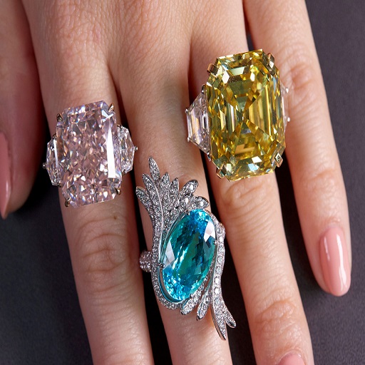 a hand with jewels on it: one jewel is yellow, one is blue and another is clear.